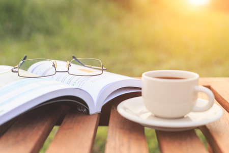 Close up glasses on book and Coffee cup on the table in the morningの写真素材