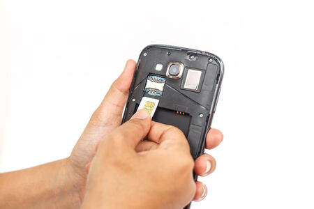 Hand holding sim card and put into smartphone isolated on white backgroundの写真素材