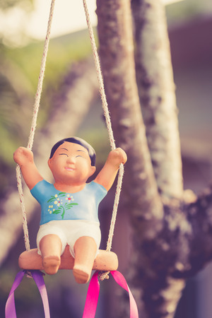 Clay doll on a swing, Vintage colorの写真素材