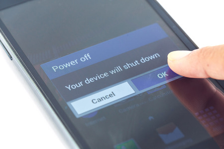 Close up finger press power off button on smartphoneの写真素材