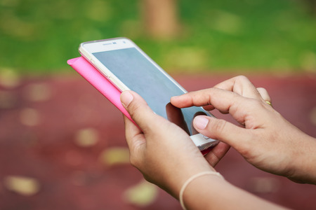 Close up hands using smartphone in the parkの写真素材