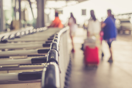 Close up trolleys luggage with blurred of passenger in airport, retro filter effectの写真素材
