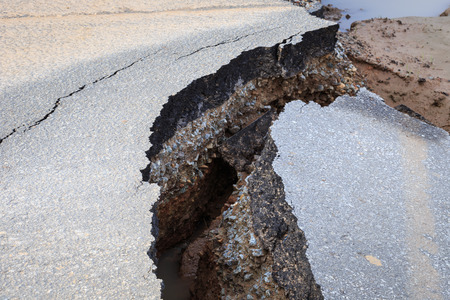 Damaged asphalt. Layer of clay that were eroded under the asphalt