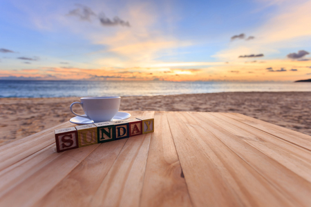 Close up text wood block and coffee cup on wood table at sunset or sunrise beachの写真素材