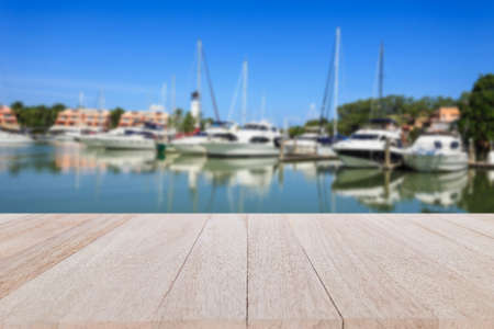 Close up top wooden table with blur of yacht stand at the harborの写真素材
