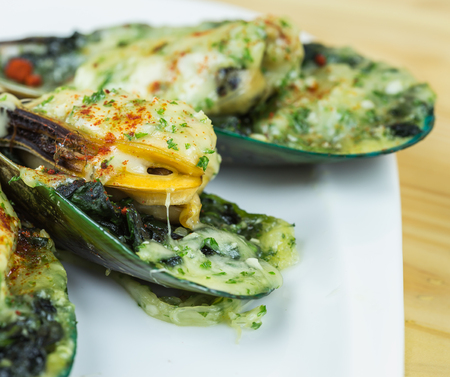 Close up mussels under cheese on wooden tableの写真素材