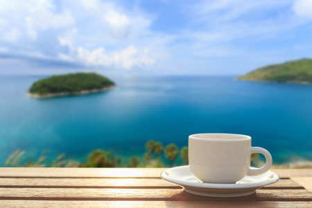 Close up coffee cup on wood table and view of tropical seaの写真素材