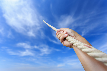 Close up hand holding rope on blur sky backgroundの写真素材