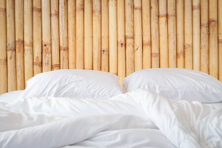 Close up white bedding sheets and pillow on wooden wall room background, Messy bed conceptの写真素材