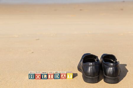 word HOLIDAY in colorful alphabet blocks and black shoe on tropical beach, Phuket Thailandの写真素材
