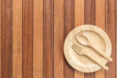 Top view empty wooden dish, fork and spoon on wooden tableの写真素材