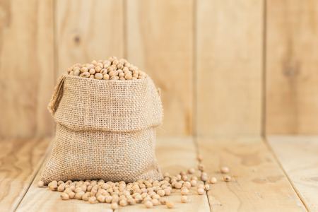 Close up soy beans in sack on wooden deskの写真素材