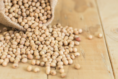 Close up soy beans in sack on wooden deskの写真素材