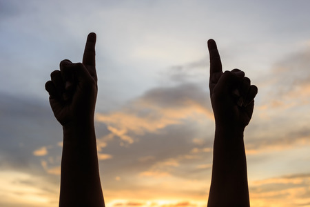 Silhouette of people hands on sky background in sunset timeの写真素材