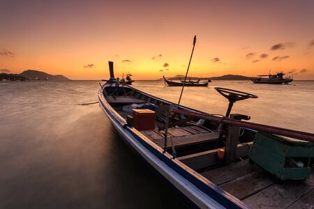 Traditional Thai longtail boat at sunrise beach in Phuket, Thailandの写真素材