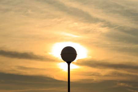 Silhouette of lamp pole on sun and sky background