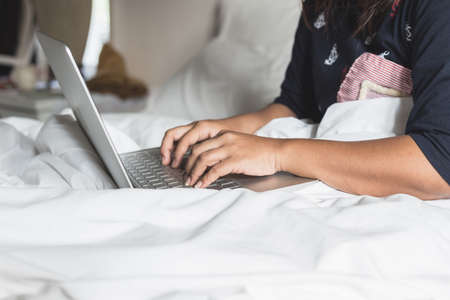 Close up woman using laptop on the bed in the morningの写真素材