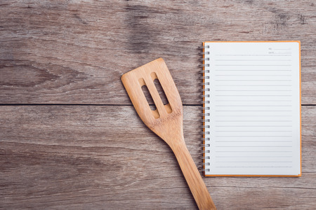 Close up cooking wooden spatula and lined paper on wooden table top viewの写真素材