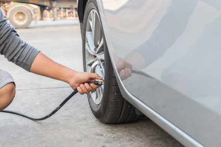 Man checking air pressure and filling air in the tires of his carの写真素材