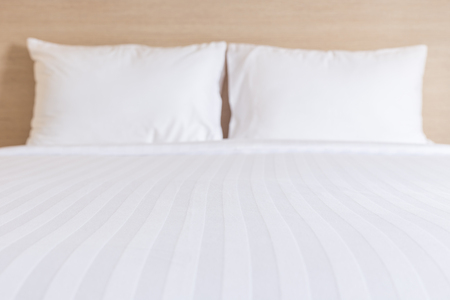Close up white bedding sheets and pillow in hotel roomの写真素材