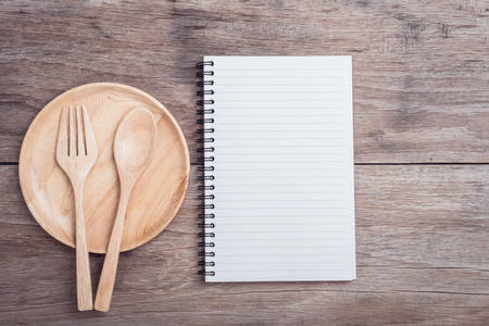 Close up wooden dish, spoon, fork and lined paper on wooden table top viewの写真素材