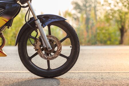 Close up front wheel of motorbike on asphalt roadの写真素材