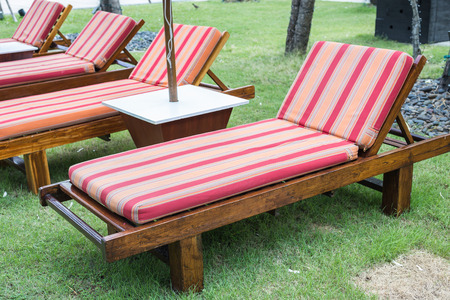 Wooden sunbed with red mattress in the garden