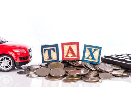 "TAX" write in colorful wood alphabet blocks  with red model car and stack of coin isolated on white backgroundの写真素材