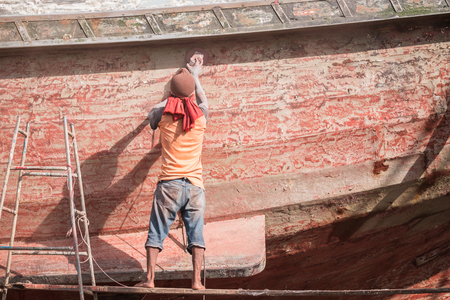 Boat Hull repairs/ A man using grinder in preparation for anti foul paint being appliedの写真素材