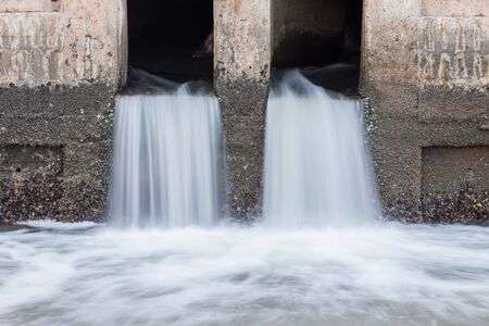 Water flowing from drain to the riverの写真素材