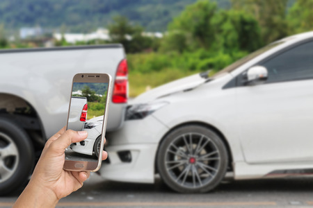 Close up hand of woman holding smartphone and take photo of car accidentの写真素材
