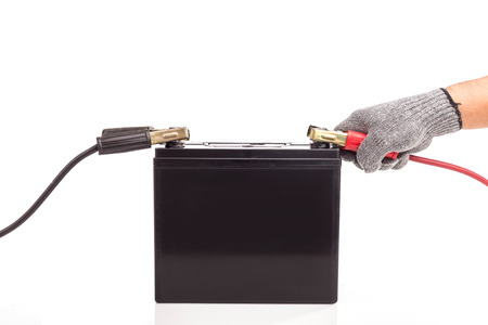 Close up hand holding car battery jump start isolated on white backgroundの写真素材