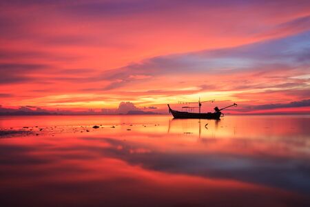 Silhouette traditional longtail boat and beautiful red sky and sunset at Samui island southern of Thailandの写真素材