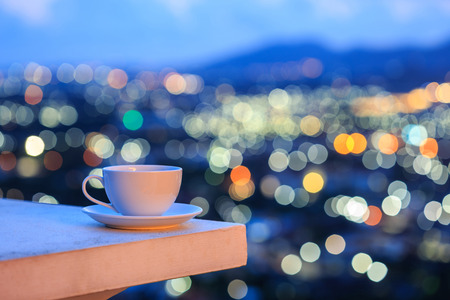 Close up white coffee cup on counter and colorful blur light bokeh of city backgroundの写真素材