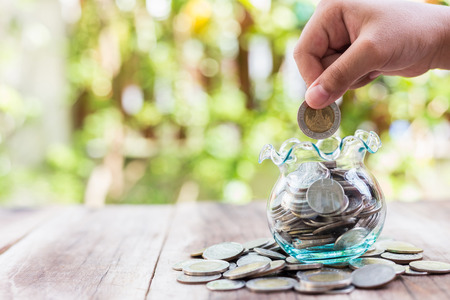Close up hand putting coins in money jar. savings concept.の写真素材