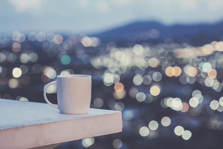 Close up white coffee cup on counter and colorful blur light bokeh of city backgroundの写真素材