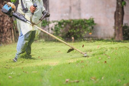 A man mowing the grass with portable machine in the gardenの写真素材