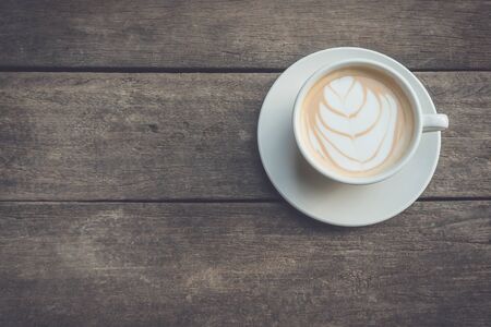 Top view hot latte coffee in white cup on wooden table background
