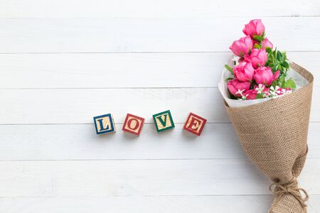LOVE write in wooden alphabet block on white wooden board background. Love concept or valentine dayの写真素材