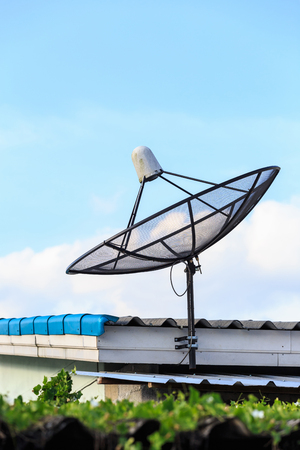 Black satellite install on the house roof with blue sky backgroundの写真素材