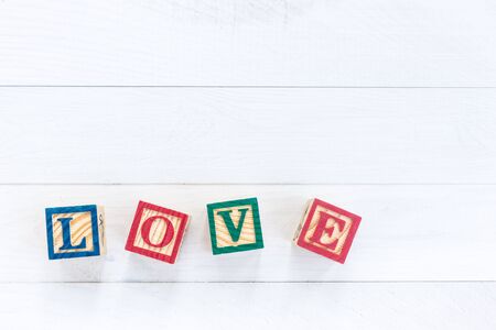 LOVE write in wooden alphabet block on white wooden board background. Love concept or valentine dayの写真素材