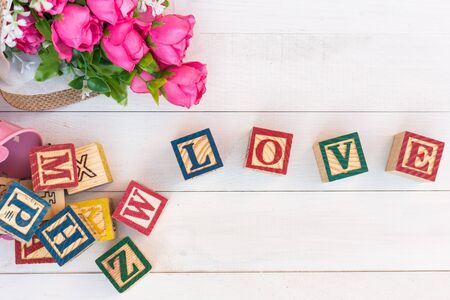 LOVE write in wooden alphabet block on white wooden board background. Love concept or valentine dayの写真素材