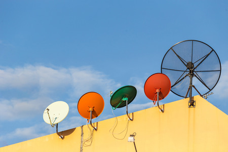 Several satellite dish installed on the house roof with blue sky backgroundの写真素材