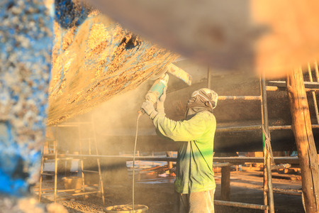 Boat Hull repairs / A man using grinder in preparation for anti foul paint being appliedの写真素材