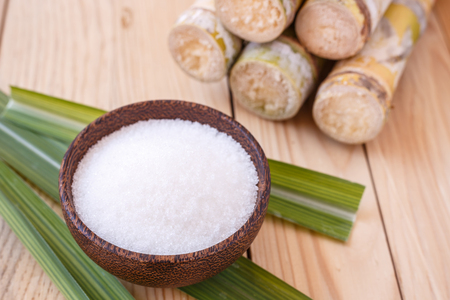 Close up white sugar and sugar cane on wooden table backgroundの写真素材