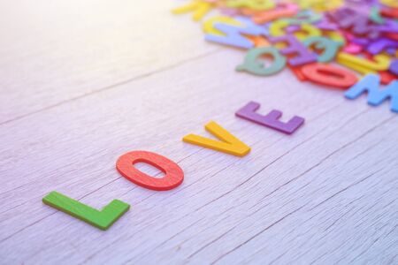 Colorful wooden alphabet and LOVE word. Top view on white wooden backgroundの写真素材
