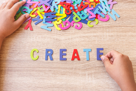 Colorful wooden alphabet and word "CREATE", Hand sort on E. Top view on grey wooden table backgroundの写真素材
