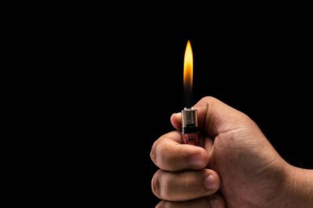 Close up hand holding burning gas lighter. Studio shot isolated on black background