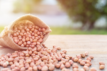 Close up peanut in small sack on wooden table. Outdoor shooting with sunlight and blur backgroundの写真素材