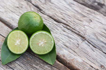Close up slice green fresh lemon on wooden table backgroundの写真素材